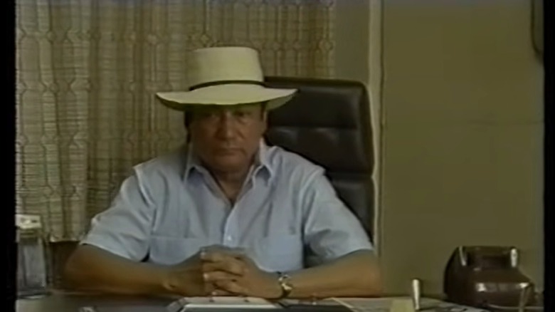 Manual Noriega in hat at desk