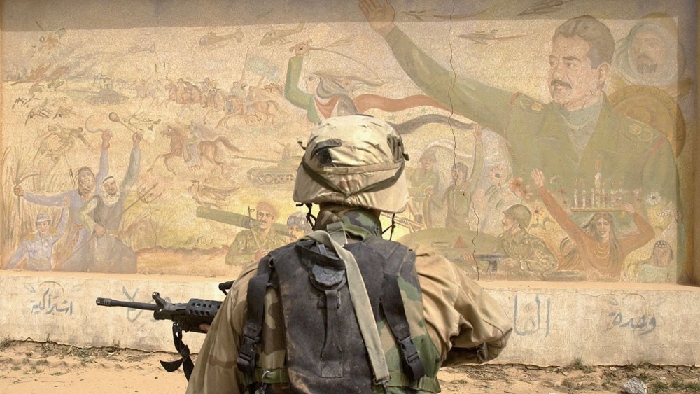 US infantry stops before a mural of Saddam Hussein after the fall of Baghdad