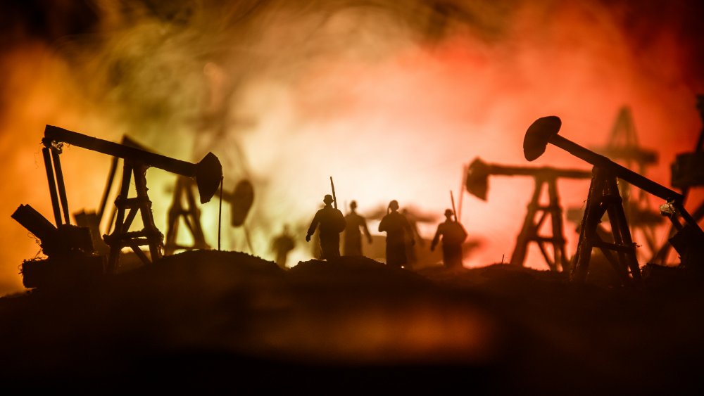 Soldier silhouettes in front of smoky oil wells