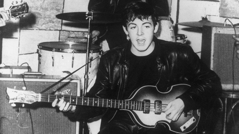 Black and white photo of young Paul McCartney playing on stage