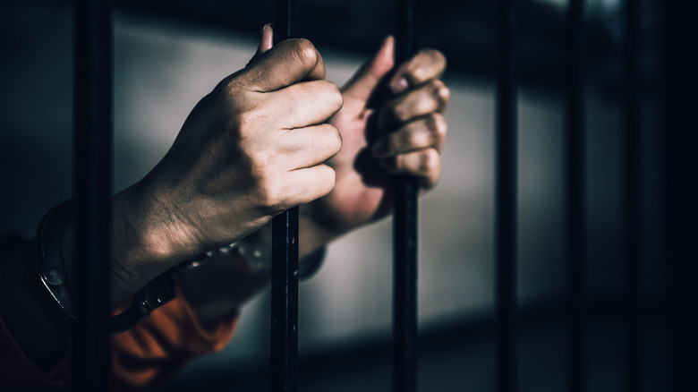 hands on bars of a jail cell