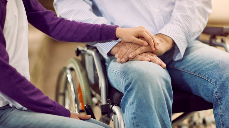 woman holding hand of person on wheelchair