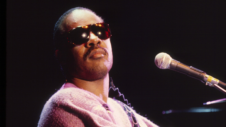 Stevie Wonder seated behind a piano and microphone