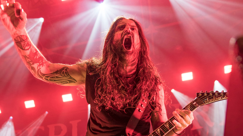 andreas kisser of sepultura screams and plays guitar on stage