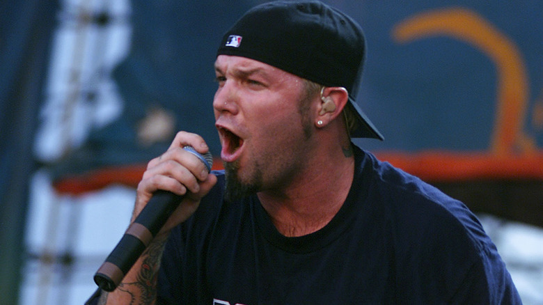 Fred Durst black baseball cap holding mic singing