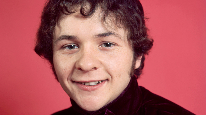 Dennis Bryon posing against a red background