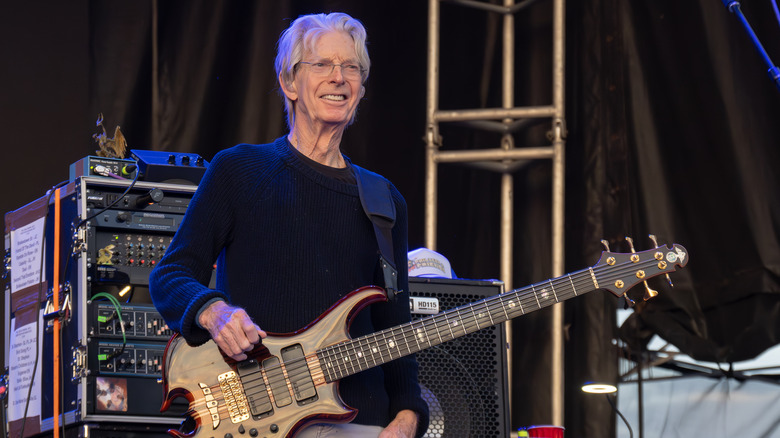 Phil Lesh holding a guitar onstage smiling