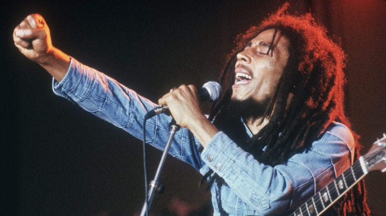 Bob Marley singing into a microphone with one fist raised