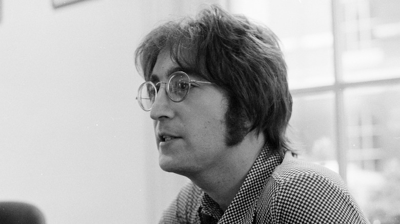 John Lennon in glasses and a collared shirt talking