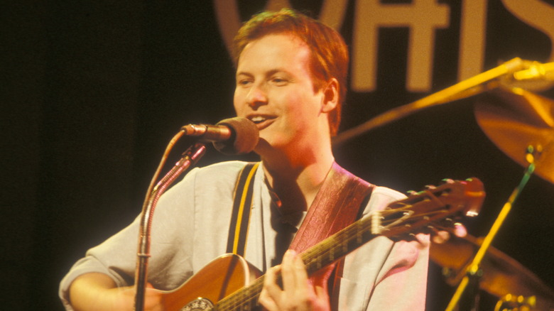 Andy Partridge holding his guitar in a garden