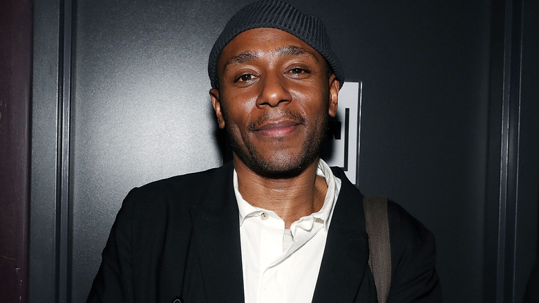 Yasiin Bey beanie dark suit smiling