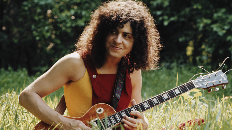 Marc Bolan playing guitar in the grass