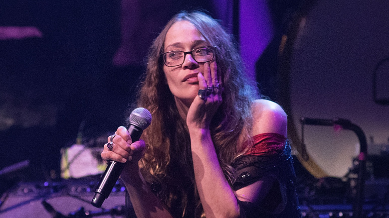 Fiona Apple holding a microphone while sitting on stage