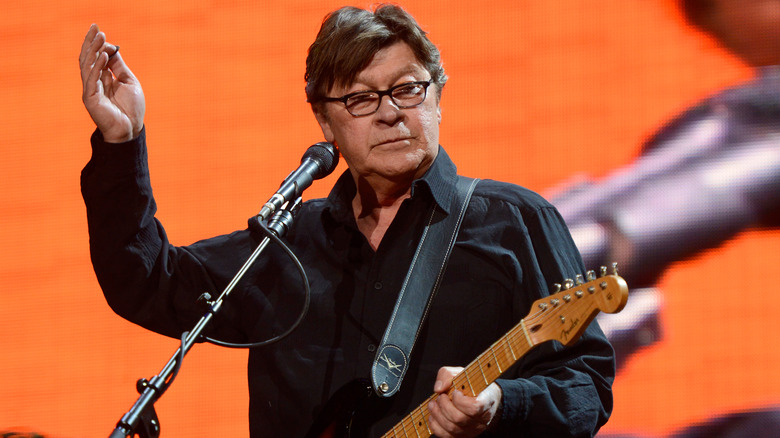 Robbie Robertson gesturing while performing onstage