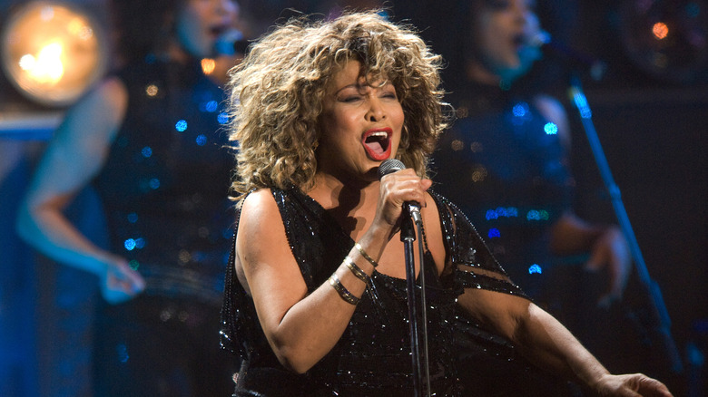 Tina Turner black dress singing microphone onstage