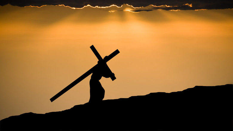 silhouette christ carrying cross on hill