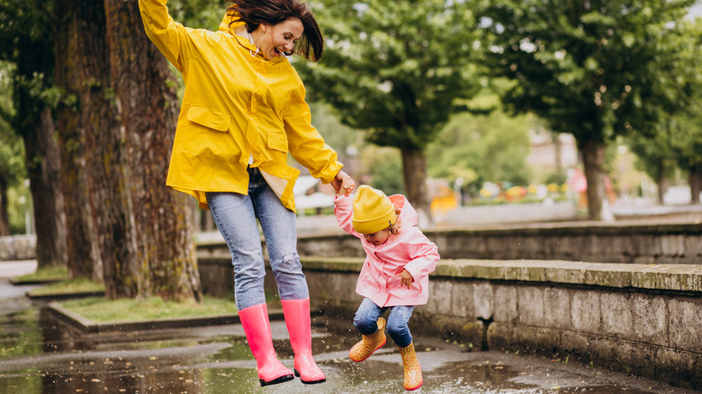 woman and child jumping in puddles