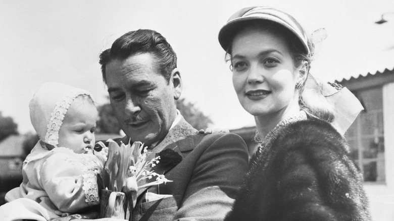 Errol Flynn holding a baby with his wife Patrice Wymore