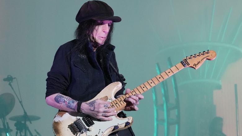 Mick Mars black hat playing guitar onstage