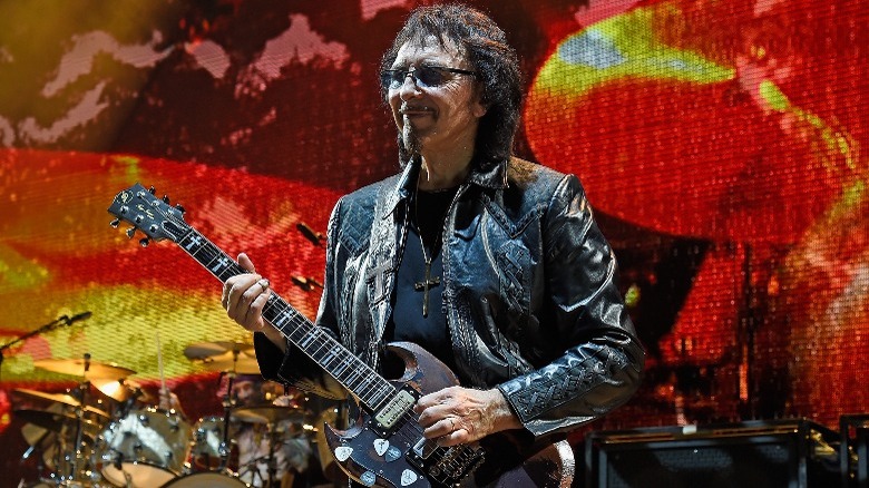 Iommi on stage leather jacket playing guitar