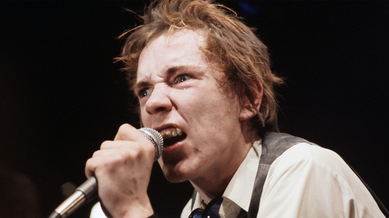 johnny rotten of the sex pistols sneering and holding a microphone