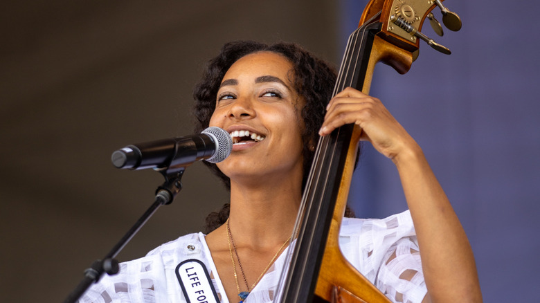 esperanza spalding smiling while singing and playing upright bass