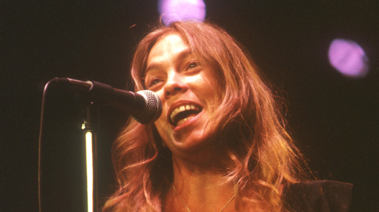 rickie lee jones smiling and singing on stage in the 1970s