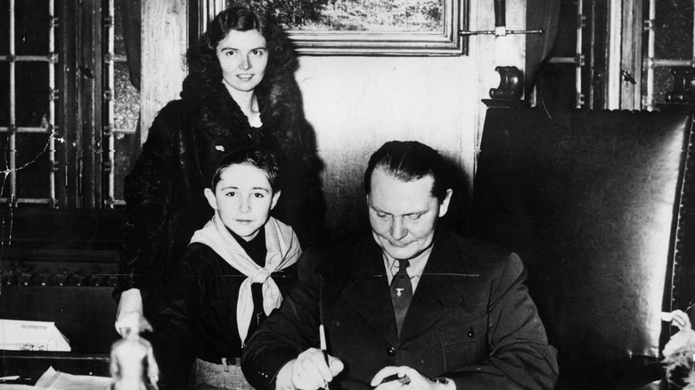 Woman and boy posing with a man signing paper in an office