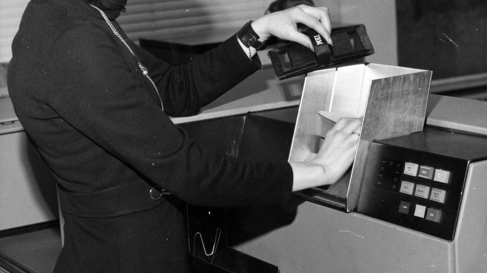 January 1970: Loading cards into the hopper of an IBM 1442 Card Read Punch. This unit is used as an input-output device with an IBM System 360 computer. 