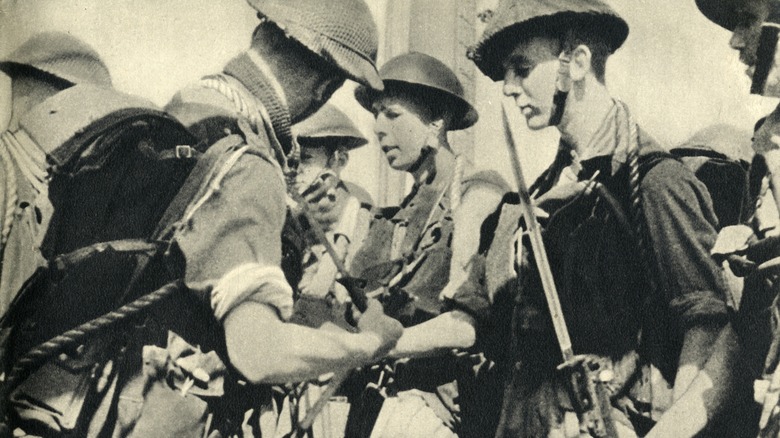 WWII soldiers standing checking equipment