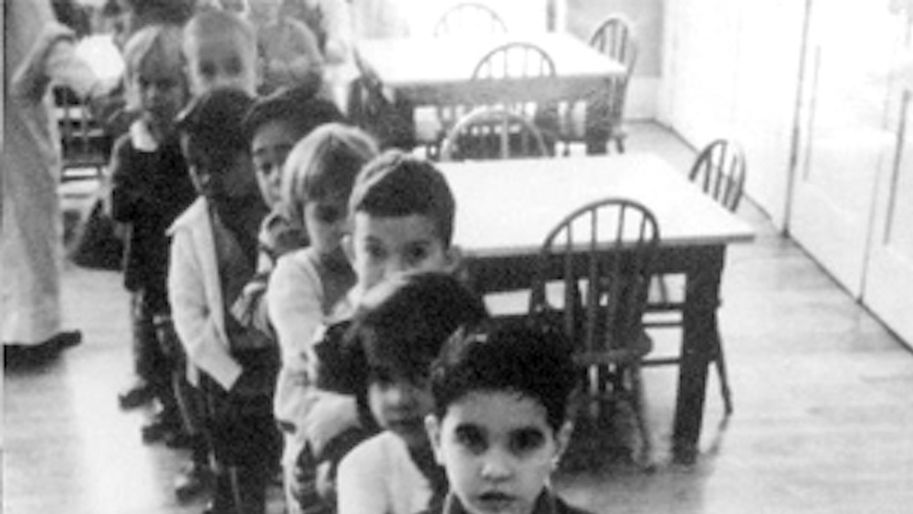 children lining up in room with tables