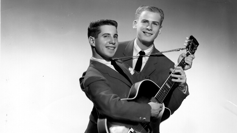 Paul Simon holding guitar with Art Garfunkle