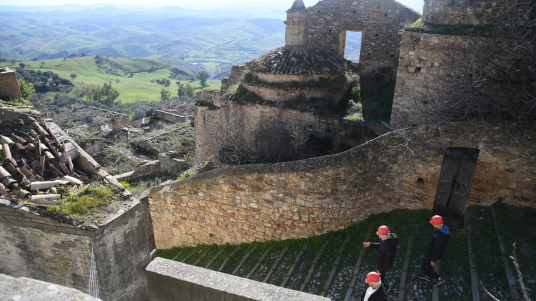 People in hard hats explore the ruins of Craco