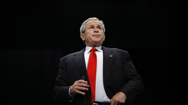 George W. Bush on stage in suit with microphone