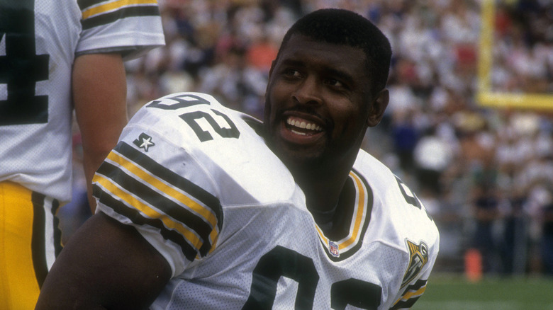 Reggie White smiling while kneeling on the sideline