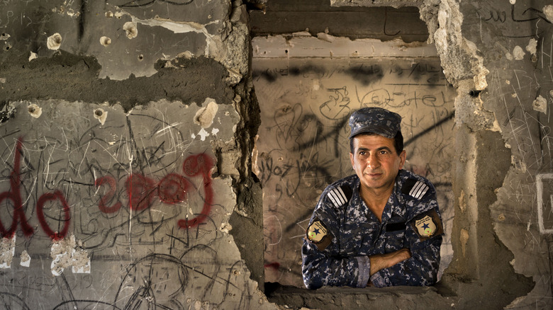 soldier in Saddam Hussein's bombed out palace bullet holes graffiti