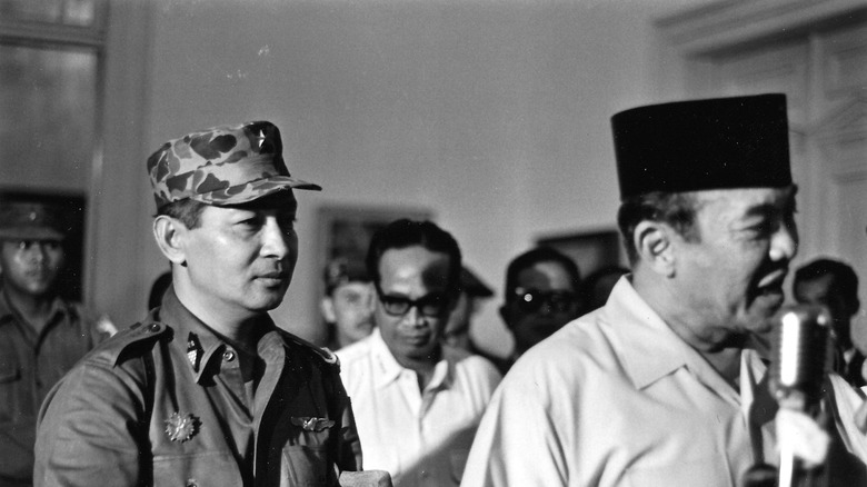 General Suharto stands with president Sukarno at microphone