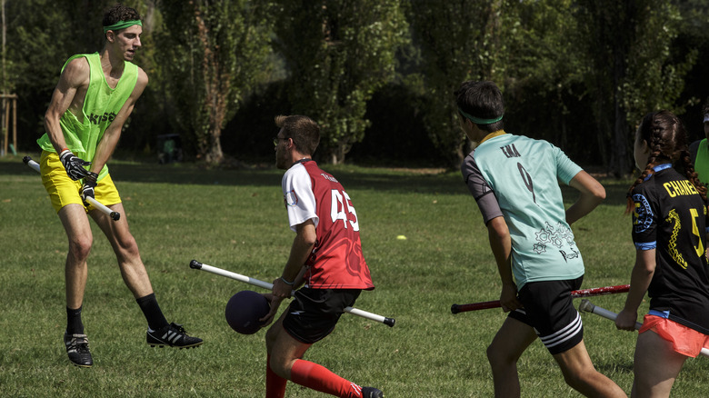 Four people playing real-life quidditch on a field