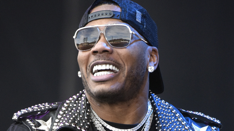 Nelly performing on stage in sunglasses and leather vest