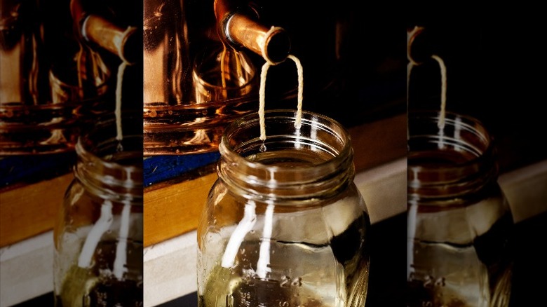 alcohol dripping into glass jar from still