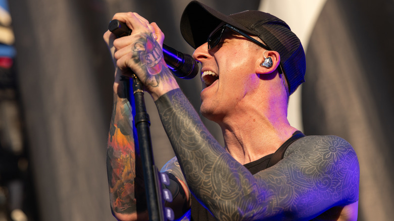 A baseball cap-wearing Ryan Key singing on stage with Yellowcard in 2024