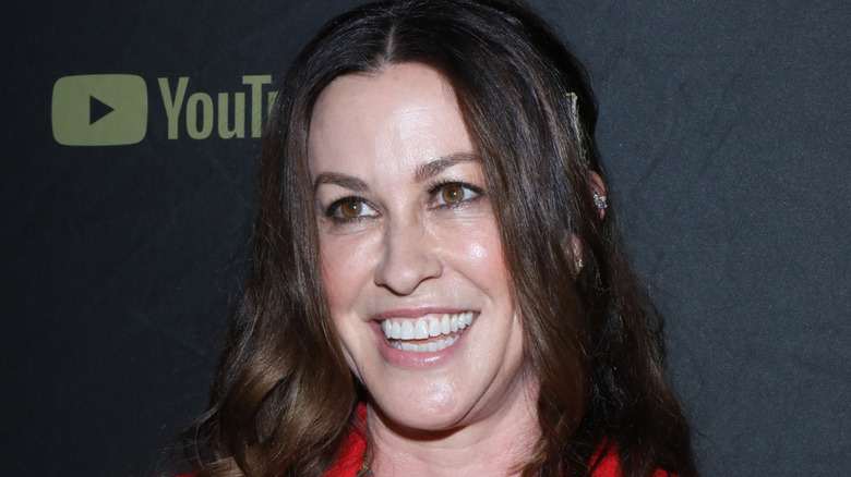 alanis morissette in red coat smiling big