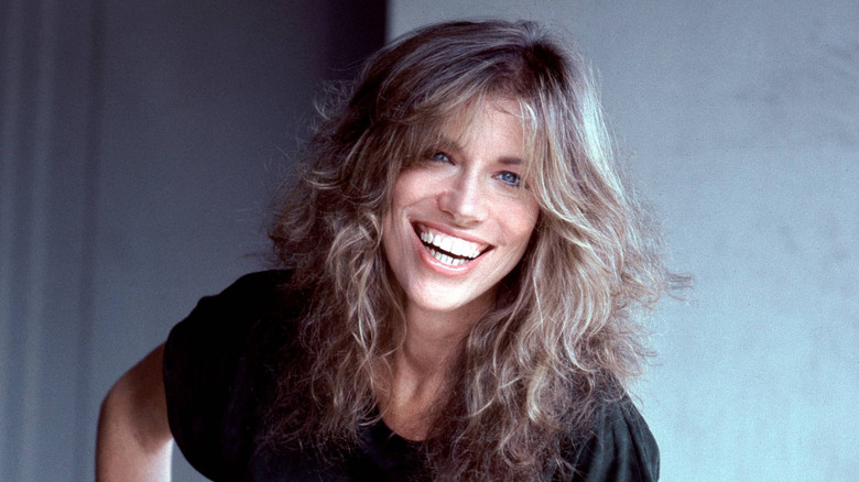 carly simon in black shirt smiling in 70s publicity shot