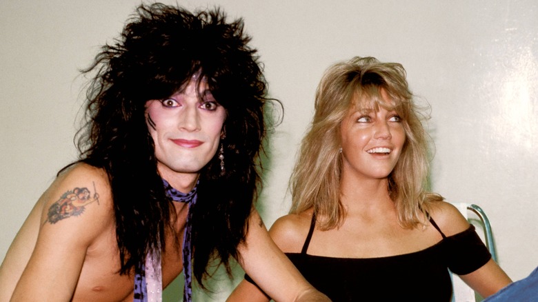 tommy lee sitting in front of heather locklear smiling