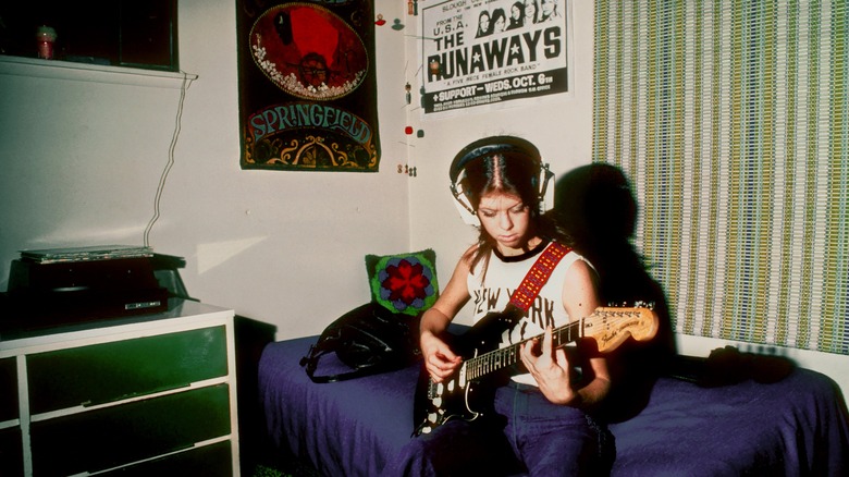 Jackie Fuchs playing guitar in her bedroom