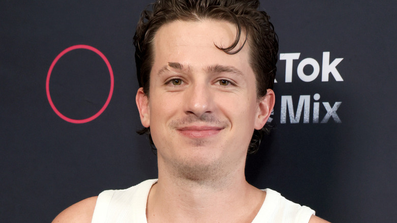 Charlie Puth smiling white vest at event