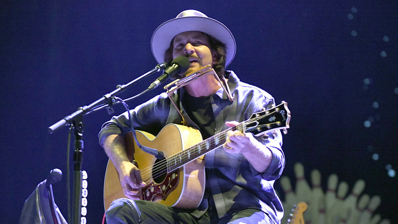 Eddie Vedder in hat sings and plays guitar