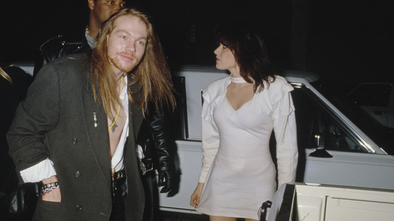 Axl Rose and Erin Everly dressed up in front of a car