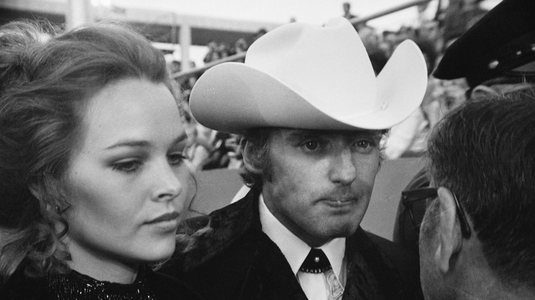 Michelle Phillips and Dennis Hopper looking stressed talking to a reporter on a red carpet