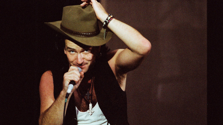 Bono wearing a hat while performing ontage with U2